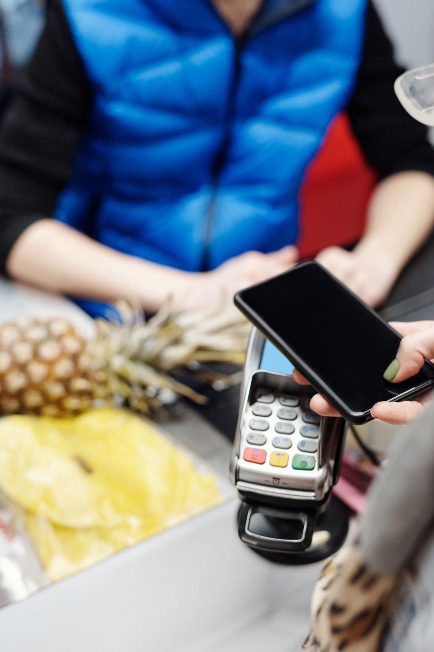Cliente pagando com o smartphone por aproximação em um caixa.